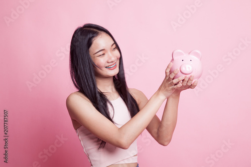 Young Asian woman with a pig coin bank.