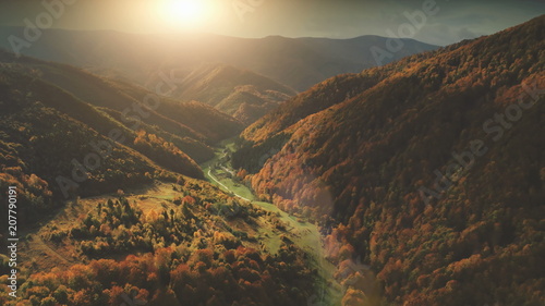 Aerial View over dramatic autumn canyon mountain landscape. Green meadows, orange hills, pine tree forests against sunset sky. Carpathians, Ukraine, Europe. Vintage retro dark toning filter.