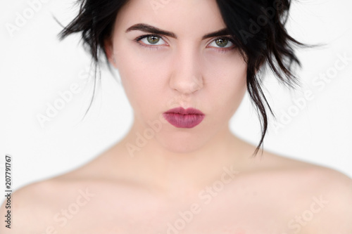 emotion face. grumpy offended woman with pursed lips and piercing glance. young beautiful brunette girl portrait on white background.