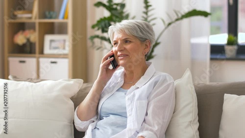 technology, communication and people concept - happy senior woman calling on smartphone at home