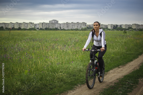 A young girl rides a bicycle away from the city