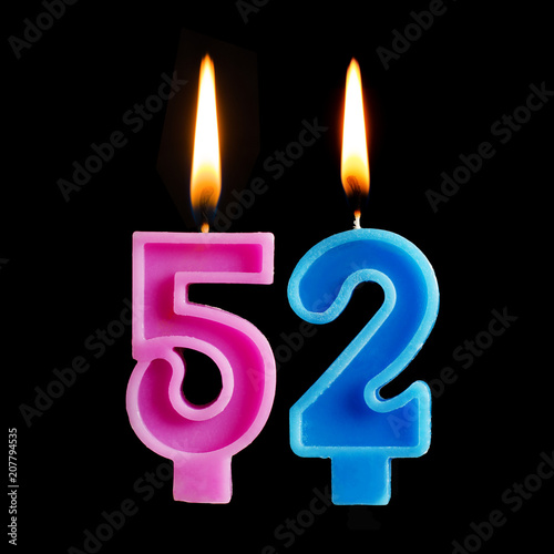 Burning birthday candles in the form of 52 fifty two for cake isolated on black background.