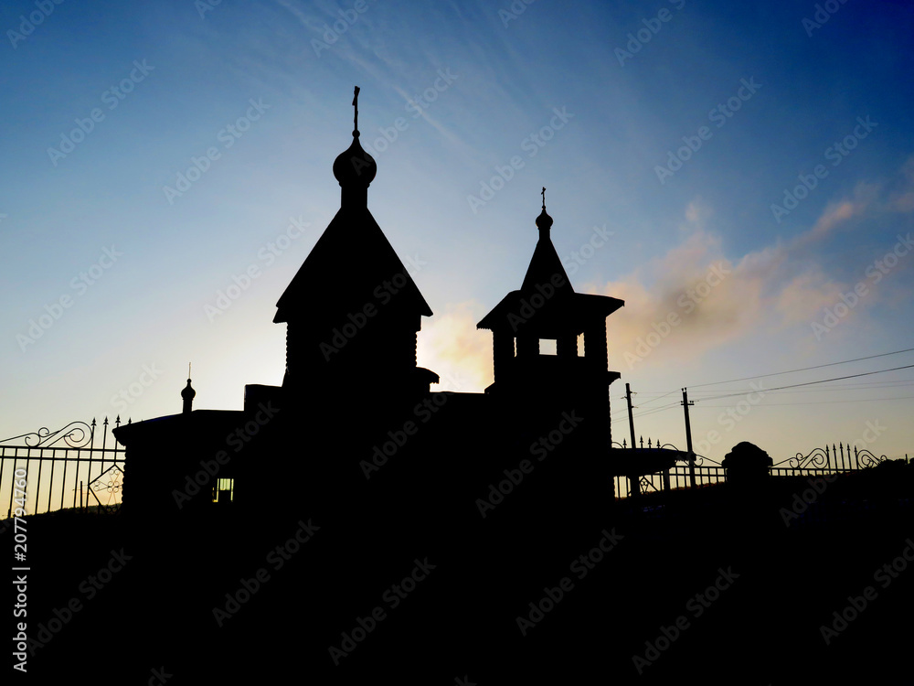 The silhouette of the Church against a beautiful blue sky. houses with crosses.