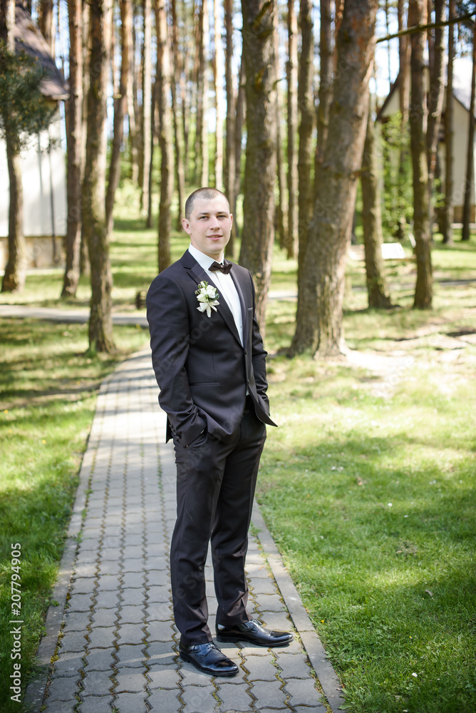 young wedding groom posing outdoors on wedding day young wedding groom posing outdoors on wedding day