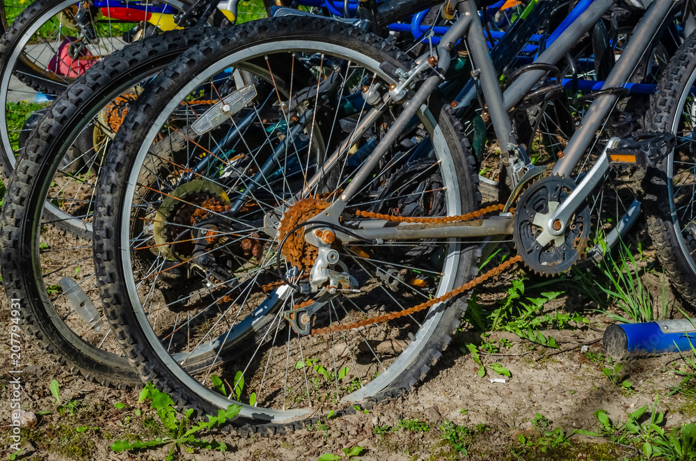 Close-up of rear wheel of a rusty deserted biycycle in a crowded blue bike rack