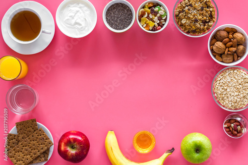 Ideas of healthy hearty breakfast for sportsmen. Fruits, oatmeal, yogurt, nuts, crispbreads, chia on pink background top view copy space