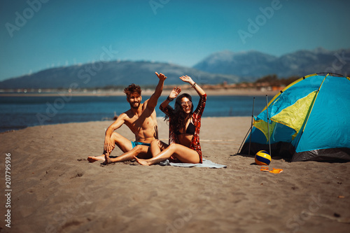Young happy couple camping on the beach during the summer