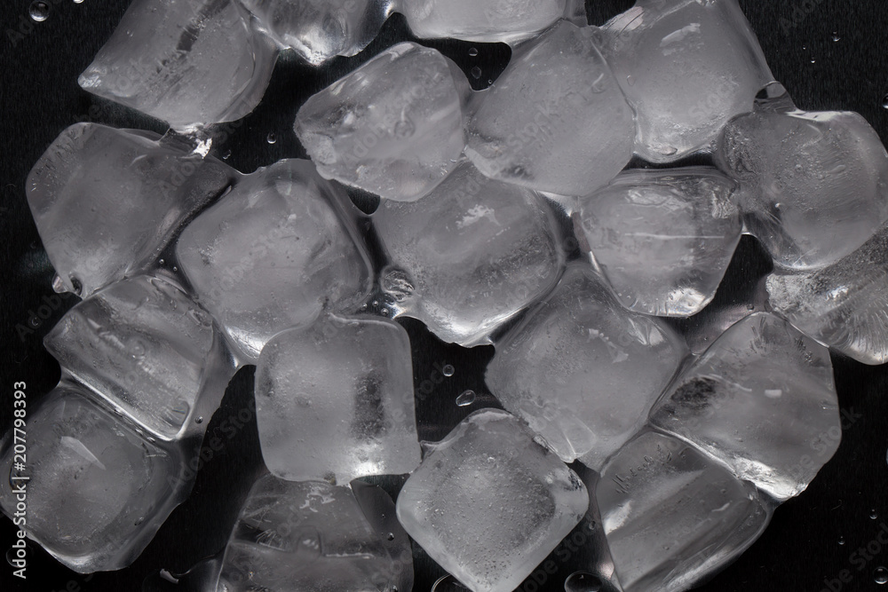 Fototapeta premium Ice cubes on a reflecting table with drops of water on a black background