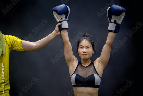 Referee lifting young female boxer hand, winner of the match. Boxing training concept