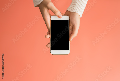 Female hands using smartphone black screen with orange background from top view. Communication concept.