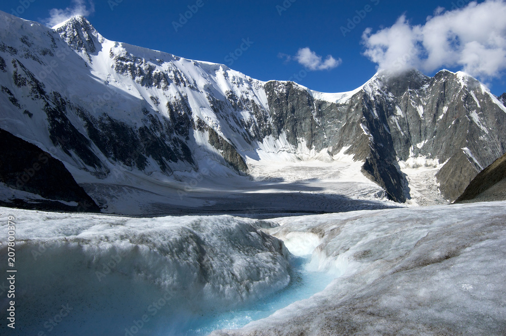 Arbuz glacier with melt water stream against mountains. Altai, Russia