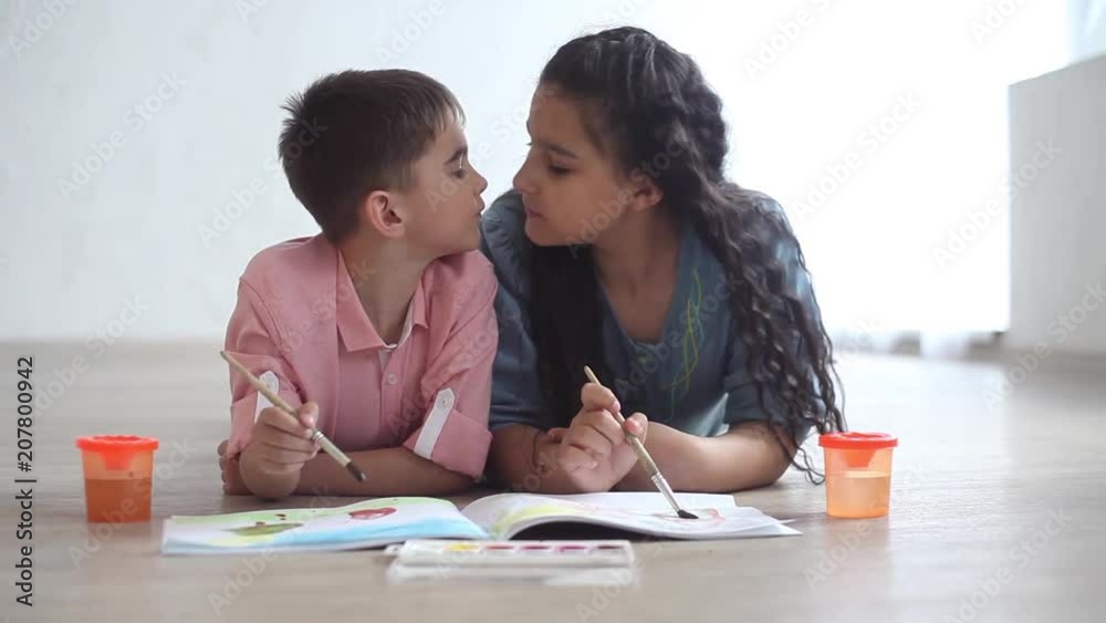 Little boy and little girl paint with paint on album lying on the floor Little boy and little girl paint with paint on album lying on the floor