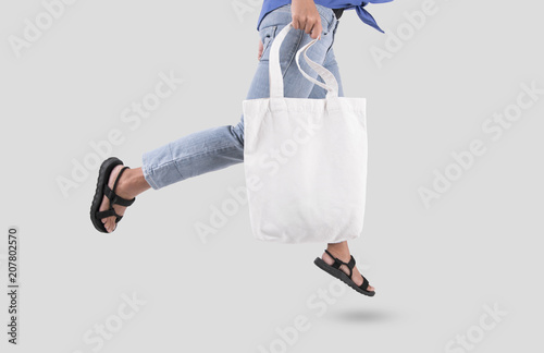 Girl is holding bag canvas fabric for mockup blank template isolated on gray background.