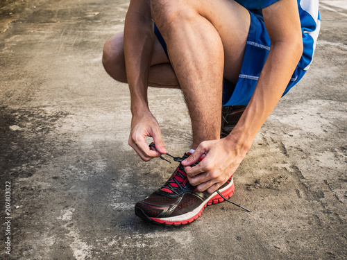 Male runner tying running shoes laces