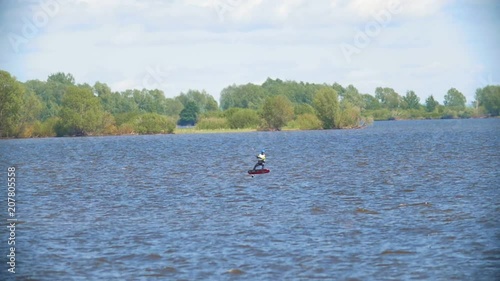 Flying kite surfer on the kiteboard over the wide river