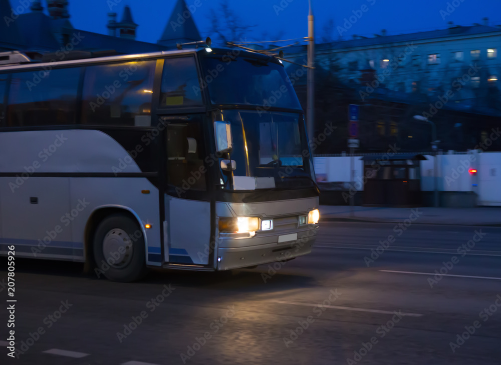 Bus moves on dark city street at night