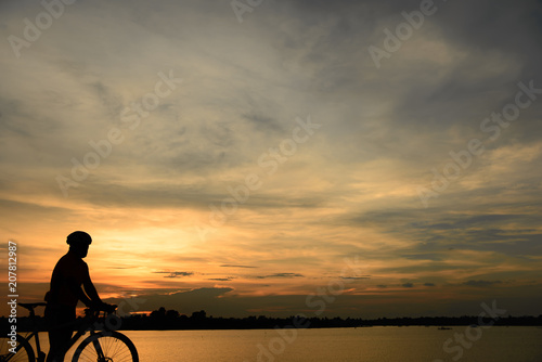 Silhouette of handsome man lift up bicycle on your head on sunset sport man concept