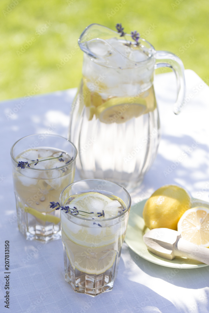 Lavender lemonade. Lavender lemonade in glass jug and cocktail glasses, on bright background Lavender lemonade. Lavender lemonade in glass jug and cocktail glasses, on bright background