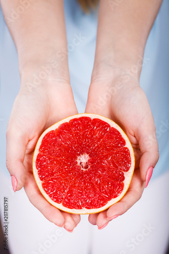 Half of red grapefruit citrus fruit in human hands