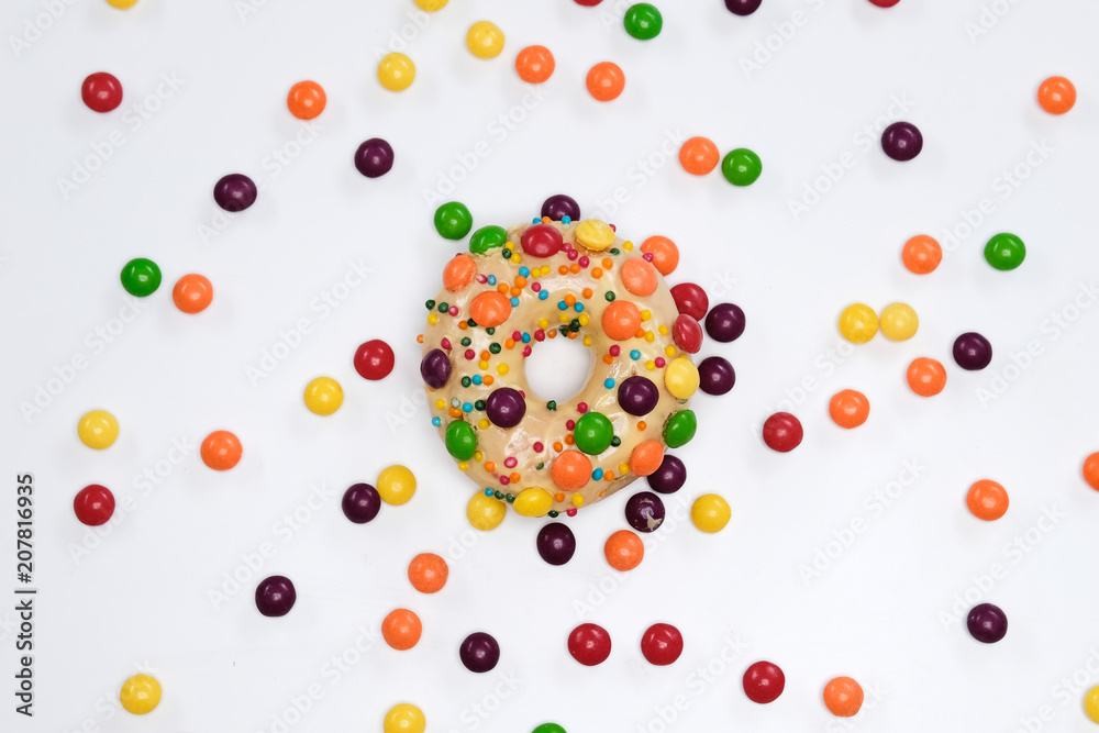 Appetizing golden donut sprinkled with colorful chocolate pellets. Appetizing golden donut sprinkled with colorful chocolate pellets.
