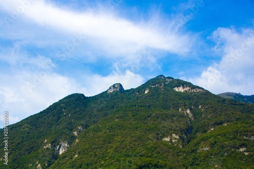 Mountain in the form of a face on Lake Como, Italy. Beautiful landscape: mountain with greens and a blue sky with clouds.