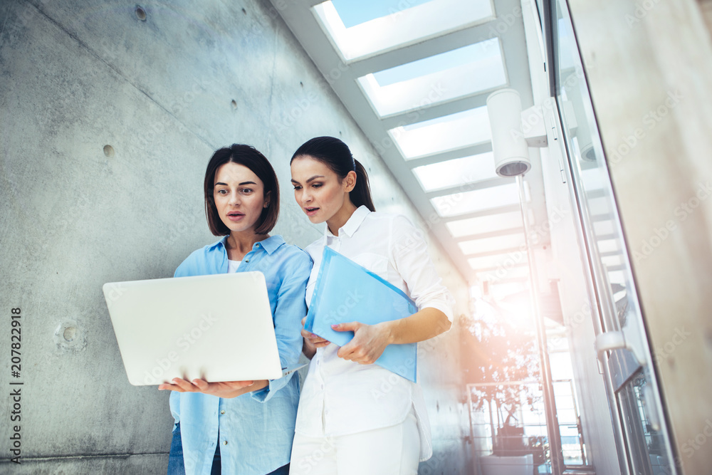 Low angle of girls with shocked expressions looking at computer. Copy space in right side Low angle of girls with shocked expressions looking at computer. Copy space in right side