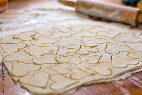 Preparation of the dough, roll out with a rolling pin and cut shapes in the form of hearts. Baking cookies for the holiday. Close-up.