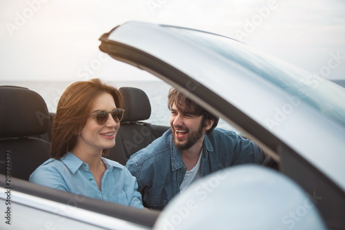 Lets go there. Cheerful romantic man is driving car with open roof while his girlfriend is sitting near him. They are travelling together while enjoying romantic vacation abroad. Relationship concept © Yakobchuk Olena