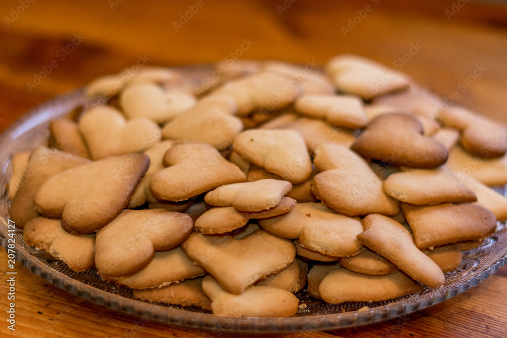 Fototapeta premium Ready-made festive shortbread cookies in the shape of hearts for Christmas and Valentine's Day, lie on a glass dish