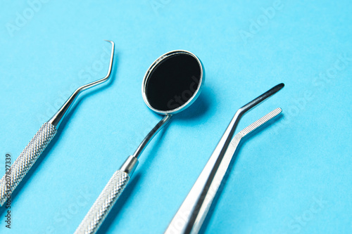 Professional Dentist tools on blue background with copy space. Dentist mirror  forceps curved  explorer curved  dental explorer angular and explorer curved with chip in dental office. Hygiene concept