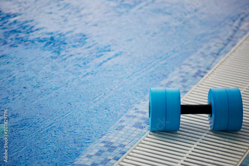 The kettlebell for water aerobics lies on the edge of the pool. Near the water. Exercise, swimming and a healthy lifestyle