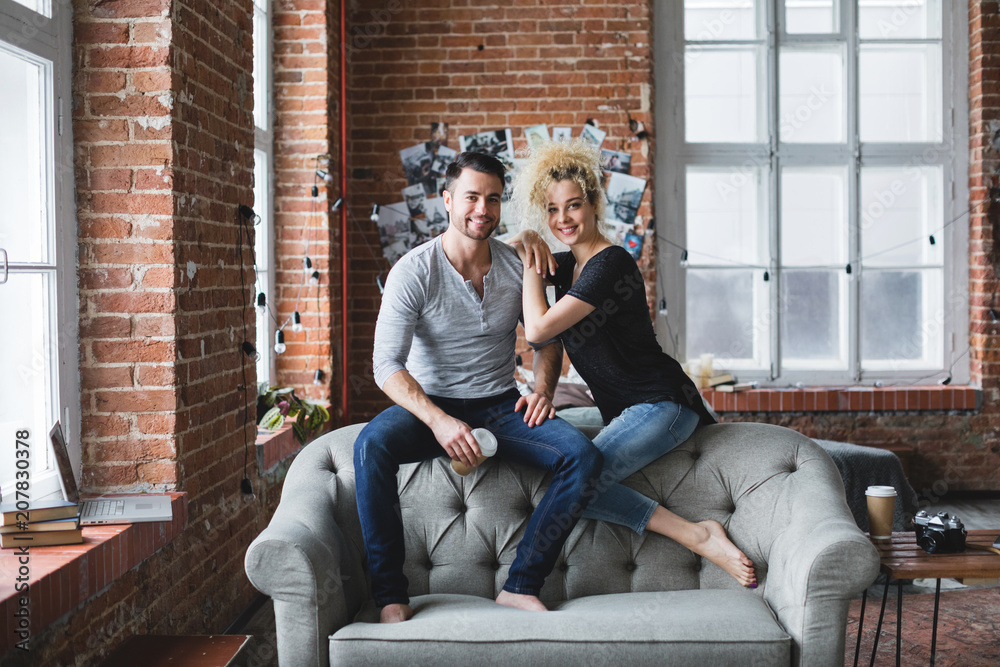 Cheerful lovely young couple on sofa at home.