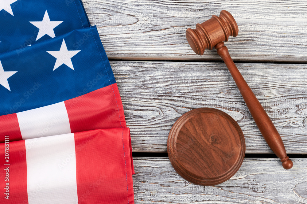 Border from American flag and wooden gavel. Justice gavel and folded flag of America on rustic wooden boards, top view.