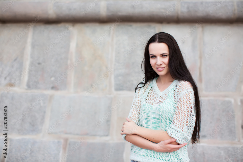 Beautiful brunette girl with long hair on the wall background.