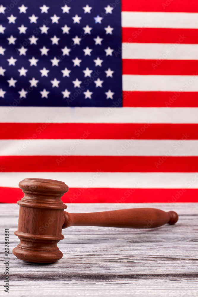 Justice gavel on USA flag background. Wooden gavel on vintage wooden table, USA flag in the background.