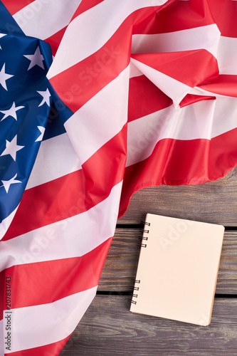 USA flag and opened notebook, top view. Flag of America and personal organizer book on wooden background, vertical image.