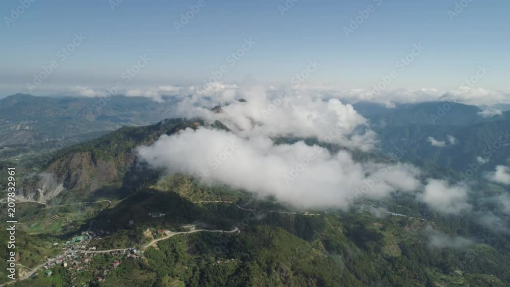 Aerial view of mountains covered forest, trees in clouds. Cordillera region. Luzon, Philippines. Slopes of mountains with evergreen vegetation. Mountainous tropical landscape. Aerial view of mountains covered forest, trees in clouds. Cordillera region. Luzon, Philippines. Slopes of mountains with evergreen vegetation. Mountainous tropical landscape.