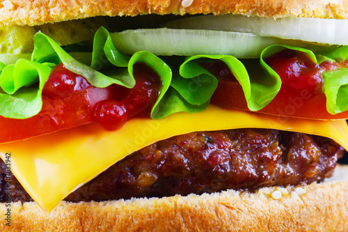 Big tasty hamburger or cheeseburger on black background with grilled meat, cheese, tomato, bacon, onion. Burger closeup