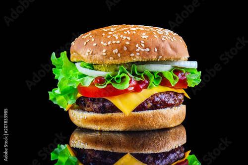 Big tasty hamburger or cheeseburger on black background with grilled meat, cheese, tomato, bacon, onion. Burger closeup