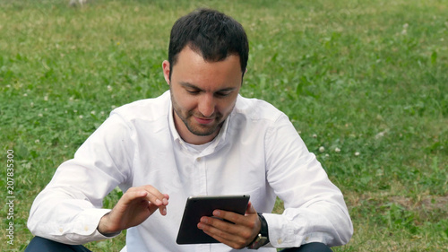 Businessman working outdoors with digital tablet PC at the park. Relaxing with a Digital Tablet outdoor