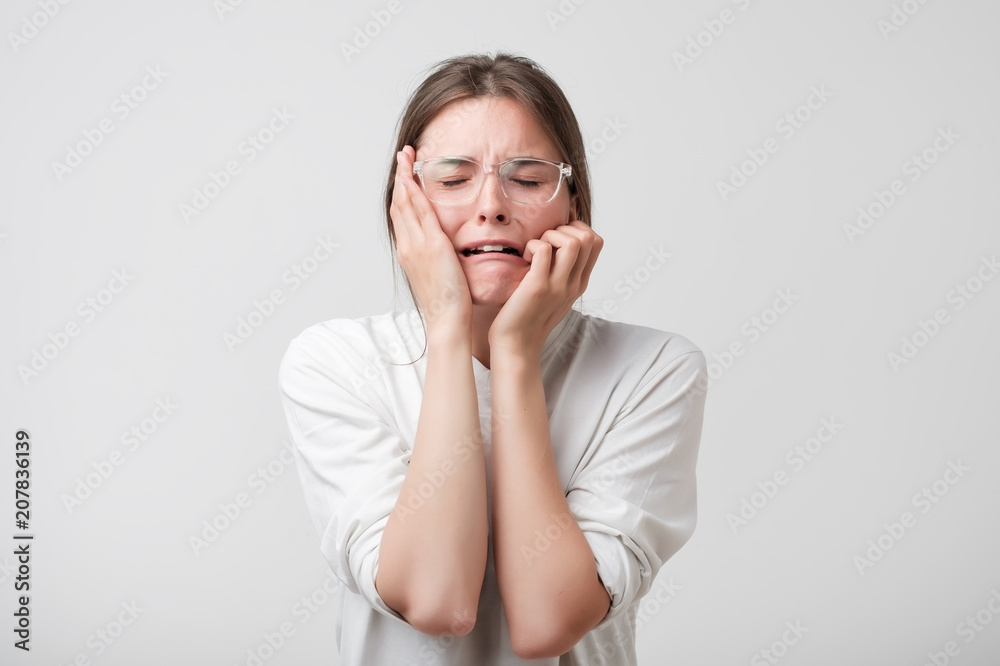 Woman in modern glasses covering ears and shouting. She is desperate because of problem at school or job Woman in modern glasses covering ears and shouting. She is desperate because of problem at school or job