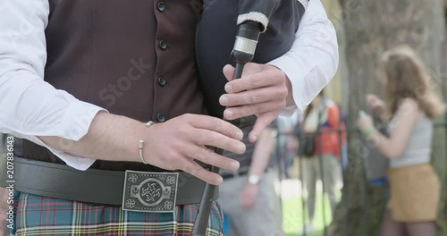 Hands of a bagpipes player in Parliament Square as traffic drives past. photo