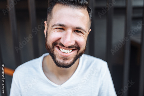 Portrait of a stylish hipster Guy, in a white blank t-shirt, on a black fence background, can be used for advertising, text insertion