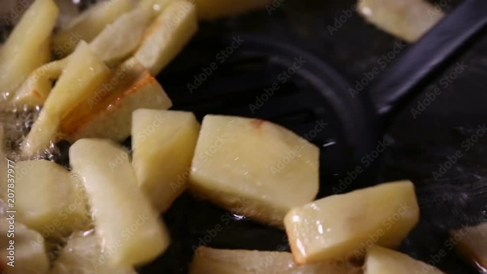 Stirring in chopped potatoes In Pan With Hot sunflower Oil - close up view Stirring in chopped potatoes In Pan With Hot sunflower Oil - close up view