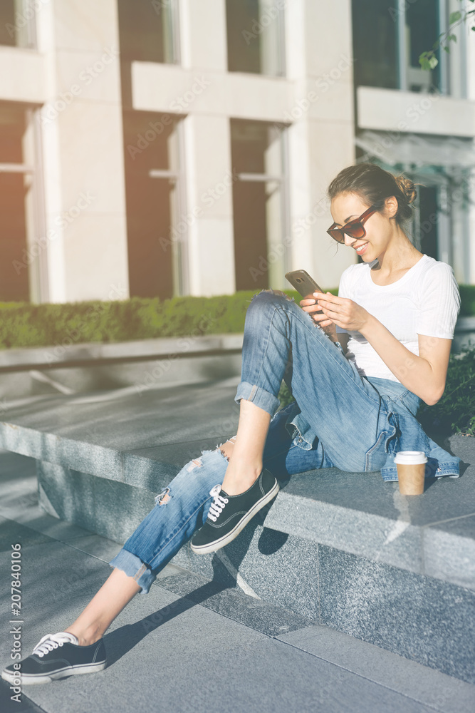 woman sitting on tne street with a phone in hands and cup of coffee woman sitting on tne street with a phone in hands and cup of coffee