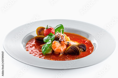Plate of tomato seafood soup on a rustic wooden table. Tasty Italian classic meal. Isolated on white.