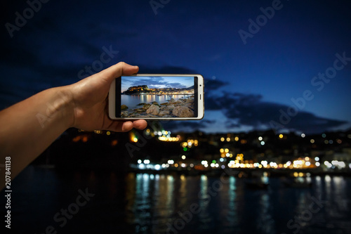 Man taking photo on mobile phone, smartphone at evening sea city photo