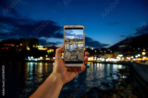 Man taking photo on mobile phone, smartphone at evening sea city photo