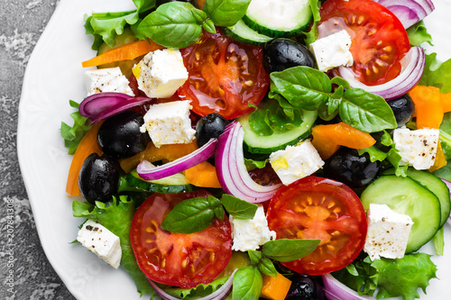 Greek salad. Fresh vegetable salad with tomato, onion, cucumbers, basil, pepper, olives, lettuce and feta cheese. Greek salad on plate