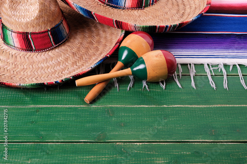 Mexico cinco de mayo fiesta carnival traditional green wood background border mexican sombrero maracas and serape rug or blanket photo